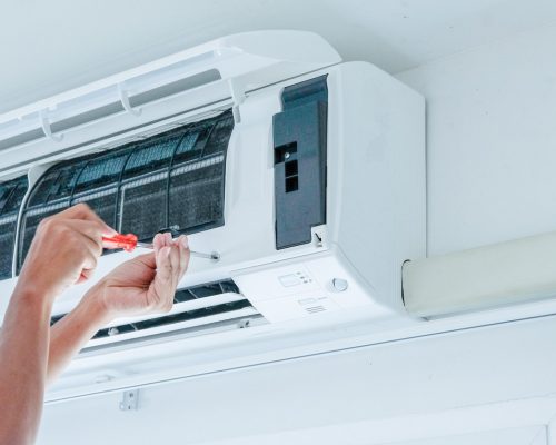 Air conditioner repairing by technician The technician under repairing the air conditioner by use screwdriver